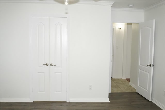 unfurnished bedroom with a closet, crown molding, and dark hardwood / wood-style floors