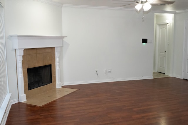 unfurnished living room with ceiling fan, ornamental molding, dark hardwood / wood-style floors, and a tile fireplace