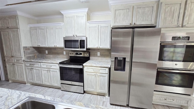 kitchen with ornamental molding, appliances with stainless steel finishes, white cabinets, and decorative backsplash