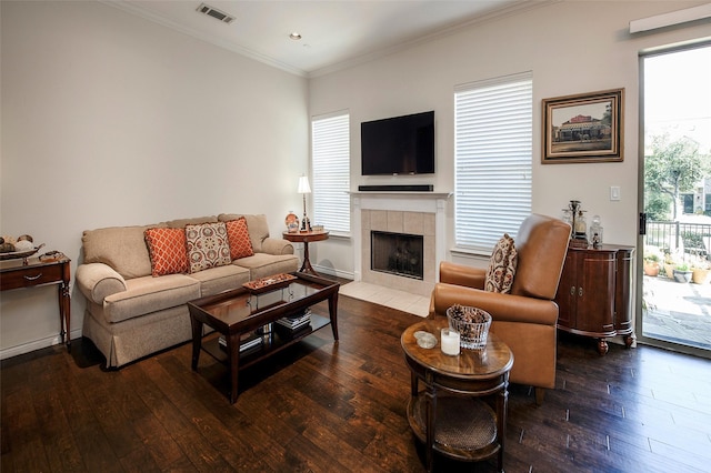 living room with a tiled fireplace, hardwood / wood-style floors, and crown molding