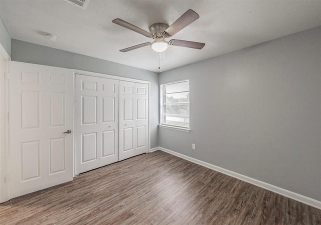 unfurnished bedroom featuring hardwood / wood-style floors, a closet, and ceiling fan