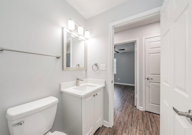 bathroom with wood-type flooring, vanity, ceiling fan, and toilet