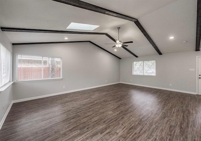 empty room featuring ceiling fan, dark wood-type flooring, and vaulted ceiling with skylight