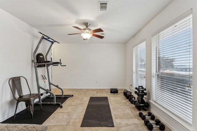 workout room featuring ceiling fan and light tile patterned flooring