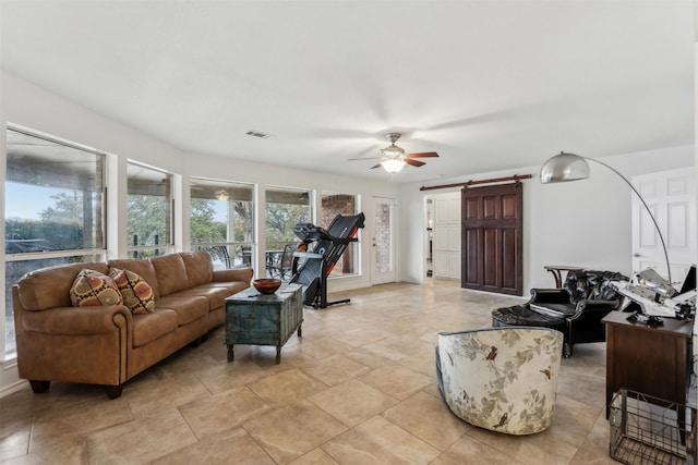 living room with a barn door and ceiling fan