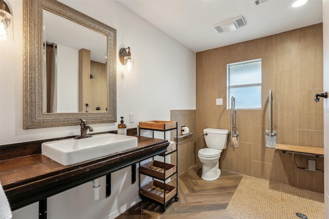 bathroom with parquet flooring, sink, tile walls, tiled shower, and toilet