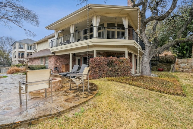 rear view of house with a lawn, a patio, and a balcony