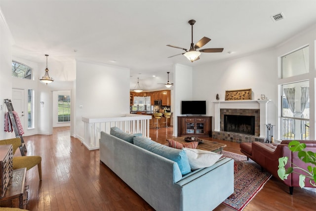 living room featuring crown molding, a brick fireplace, and dark hardwood / wood-style flooring