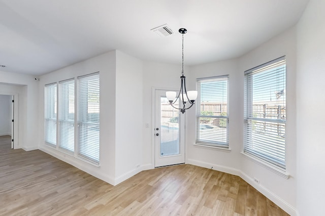 unfurnished dining area featuring plenty of natural light, light hardwood / wood-style floors, and a notable chandelier