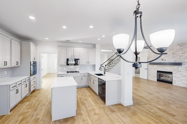 kitchen with sink, white cabinetry, light stone counters, a fireplace, and black appliances