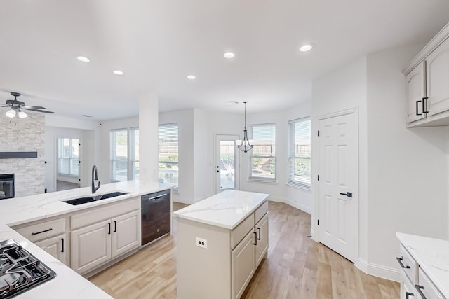 kitchen featuring sink, dishwasher, white cabinetry, a kitchen island, and decorative light fixtures