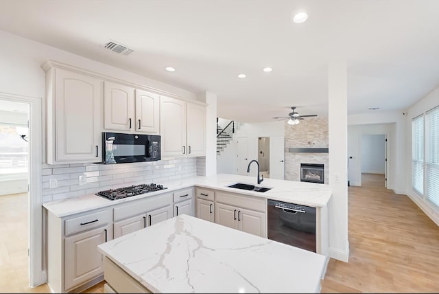 kitchen featuring white cabinetry, kitchen peninsula, sink, and black appliances