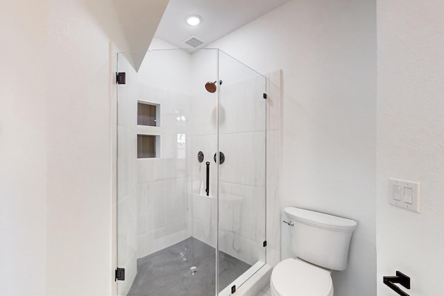 bathroom featuring toilet and a shower with door