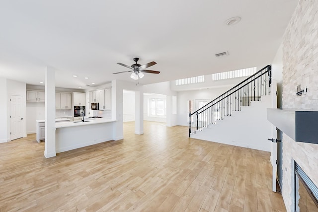 living room featuring a tiled fireplace, light hardwood / wood-style flooring, and ceiling fan