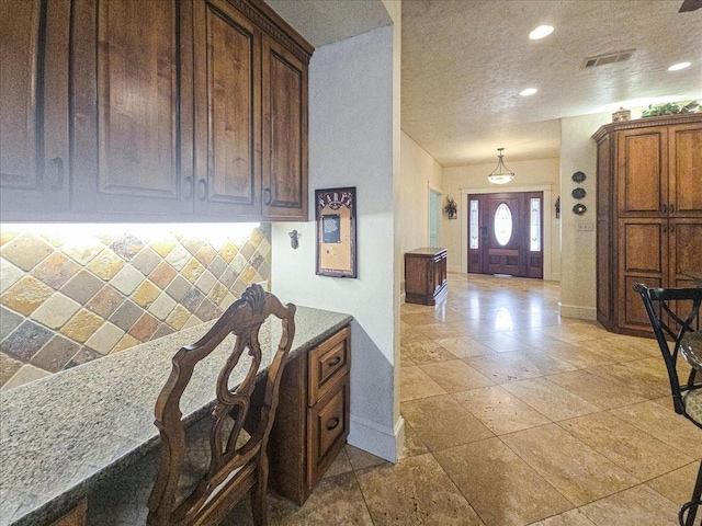 kitchen featuring light stone countertops, a textured ceiling, and decorative backsplash