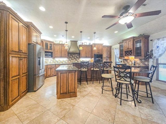 kitchen featuring a breakfast bar area, decorative light fixtures, custom range hood, a kitchen island, and stainless steel appliances