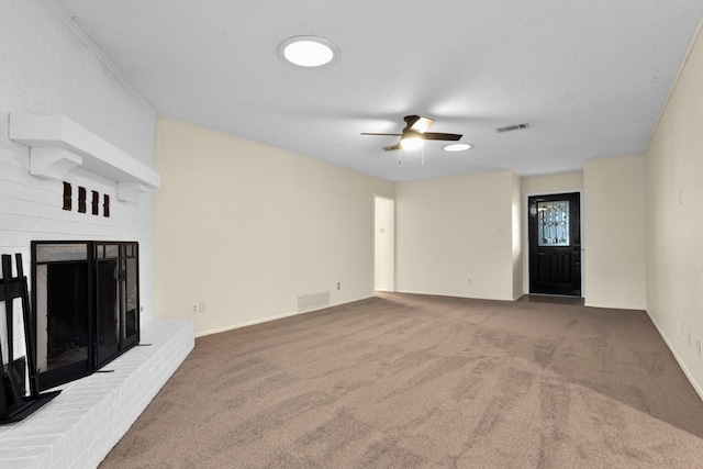 unfurnished living room featuring ceiling fan, a fireplace, carpet floors, and a textured ceiling