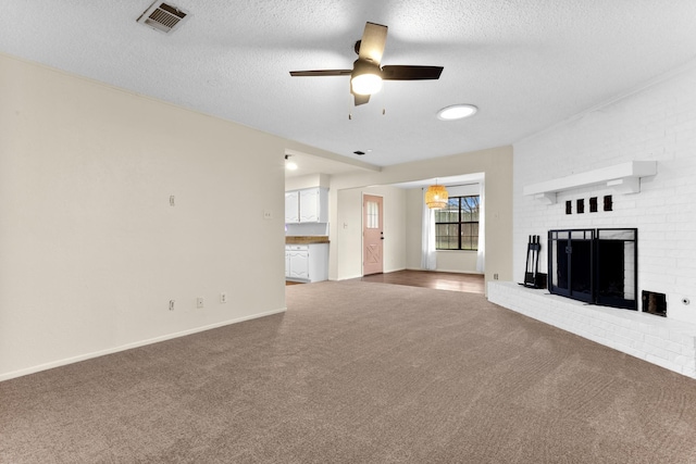 unfurnished living room featuring ceiling fan, a brick fireplace, a textured ceiling, and dark carpet