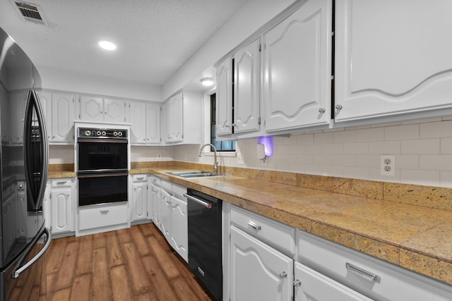 kitchen featuring dark wood-type flooring, sink, black appliances, a textured ceiling, and white cabinets