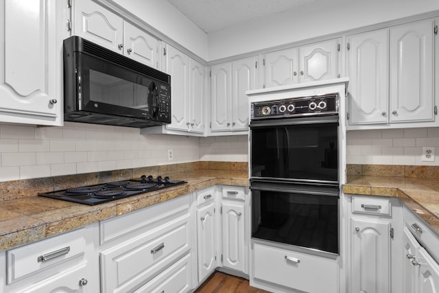 kitchen featuring white cabinetry, backsplash, light hardwood / wood-style floors, and black appliances