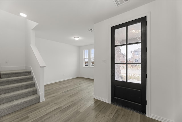 foyer entrance with light wood-style floors, visible vents, stairway, and baseboards