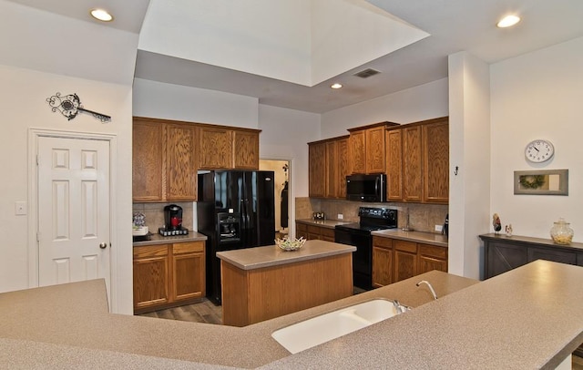 kitchen featuring tasteful backsplash, wood-type flooring, sink, a center island, and black appliances