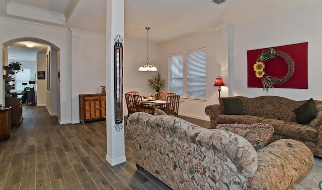 living room featuring dark hardwood / wood-style flooring, a notable chandelier, and ornamental molding