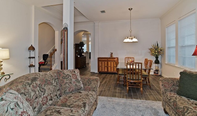 living room featuring ornate columns, ornamental molding, and an inviting chandelier