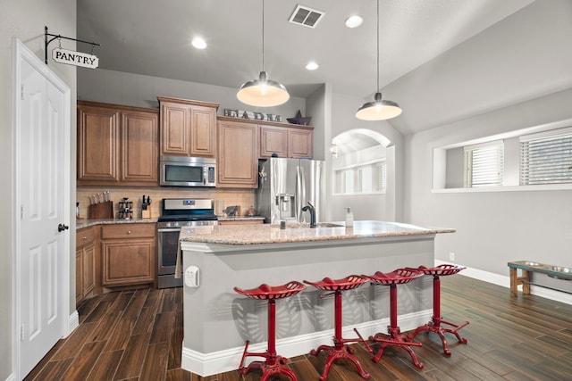 kitchen featuring stainless steel appliances, dark hardwood / wood-style floors, a kitchen island with sink, and hanging light fixtures