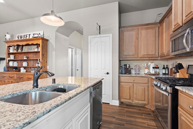 kitchen with sink, tasteful backsplash, light stone counters, hanging light fixtures, and stainless steel appliances