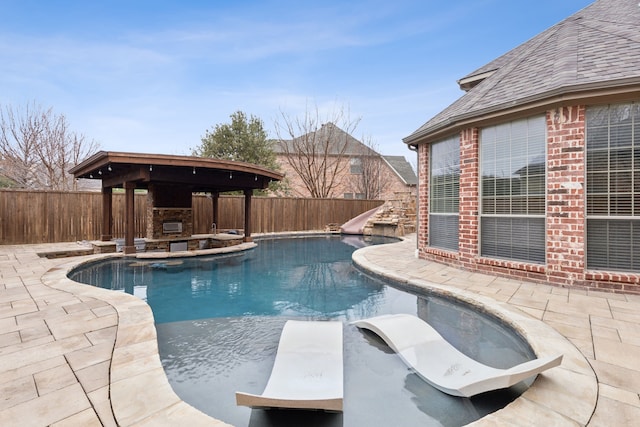 view of swimming pool with a diving board, a fireplace, a water slide, a gazebo, and a patio area