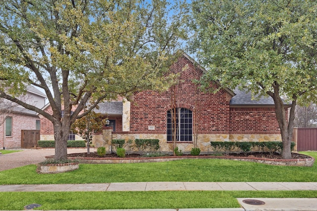 900 Thimbleberry Dr, Mckinney, TX 75071 - view of front of house with brick siding, fence, stone siding, a front yard, and roof with shingles