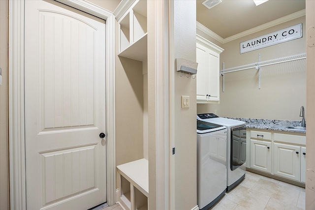 clothes washing area featuring sink, crown molding, light tile patterned floors, cabinets, and separate washer and dryer