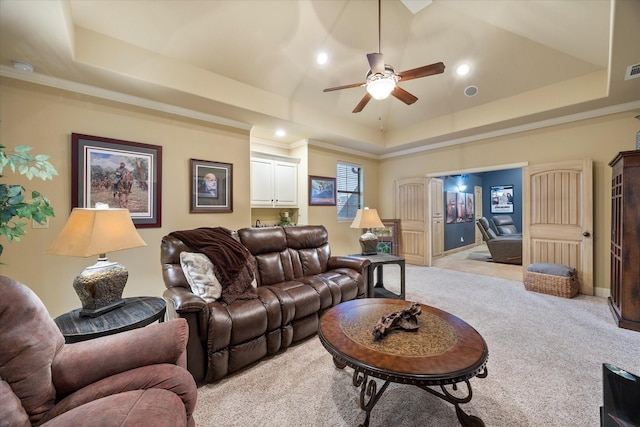 carpeted living room featuring crown molding, a tray ceiling, and ceiling fan