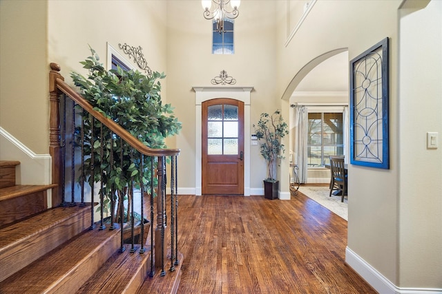 foyer entrance featuring dark wood-type flooring, a chandelier, and a towering ceiling