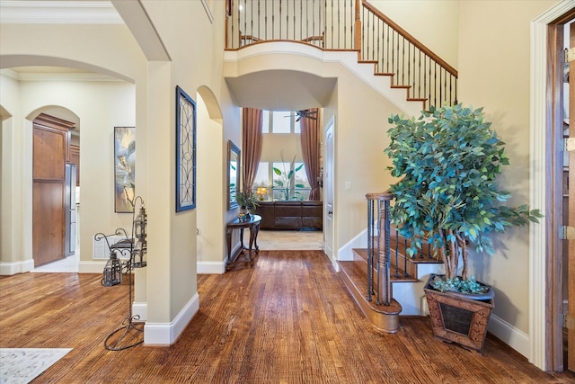 entrance foyer with crown molding, hardwood / wood-style flooring, and a towering ceiling