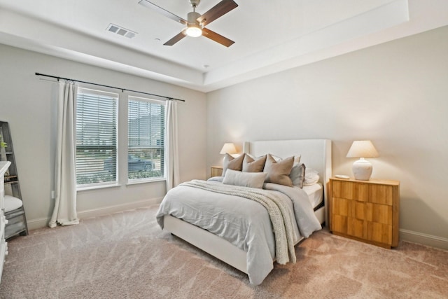 bedroom featuring ceiling fan, light colored carpet, and a raised ceiling