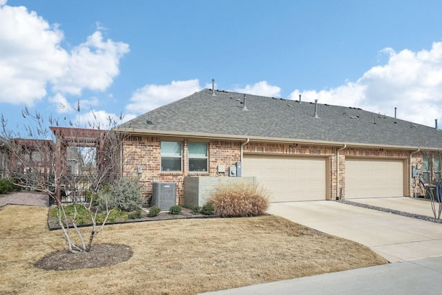 view of front facade featuring a garage, central AC unit, and a front lawn