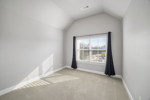 carpeted spare room featuring vaulted ceiling