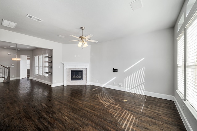 unfurnished living room featuring dark hardwood / wood-style flooring, a high end fireplace, ceiling fan, and plenty of natural light