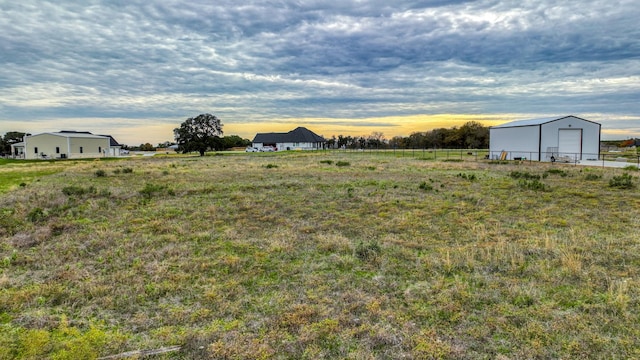 yard at dusk featuring a rural view