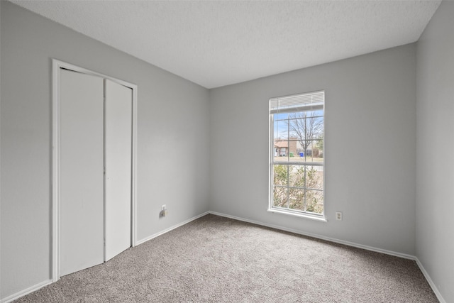 unfurnished bedroom with a closet, a textured ceiling, and carpet flooring