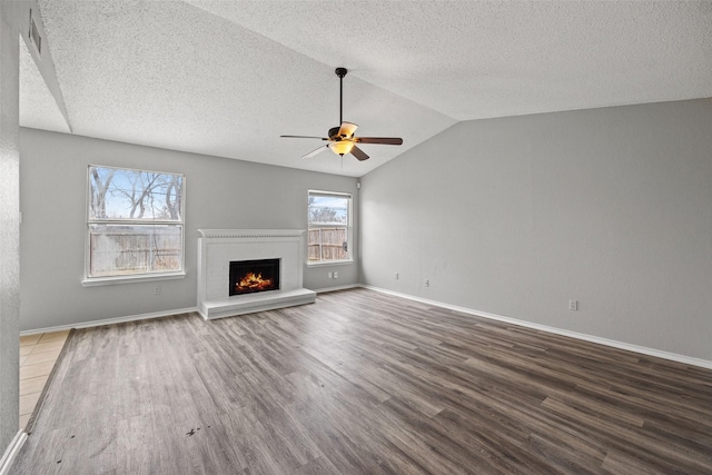 unfurnished living room with dark wood-type flooring, ceiling fan, vaulted ceiling, and a textured ceiling