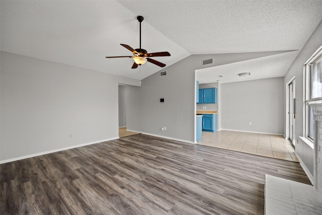 unfurnished living room with vaulted ceiling, hardwood / wood-style floors, a textured ceiling, and ceiling fan