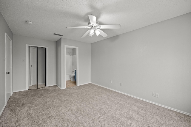 unfurnished bedroom featuring light carpet, ceiling fan, a textured ceiling, and ensuite bathroom