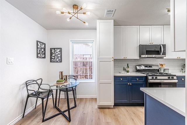 kitchen with light hardwood / wood-style flooring, white cabinetry, backsplash, stainless steel appliances, and blue cabinets