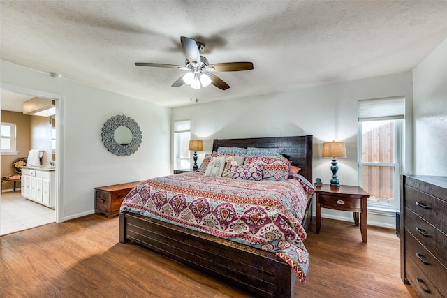 bedroom featuring ceiling fan, connected bathroom, a textured ceiling, and light hardwood / wood-style floors