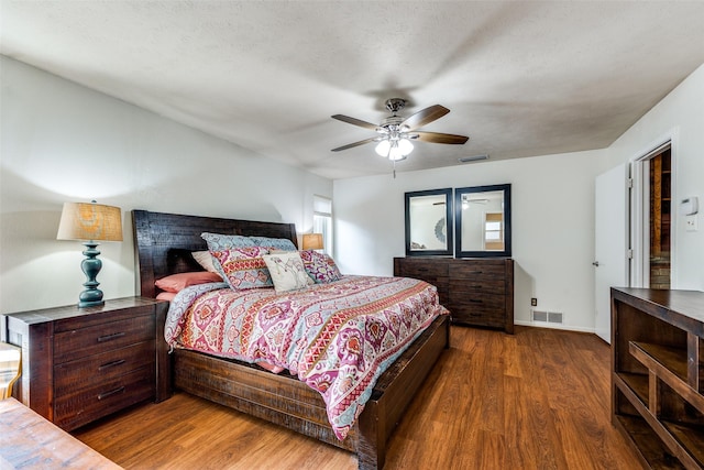 bedroom featuring ceiling fan, dark hardwood / wood-style floors, and a textured ceiling