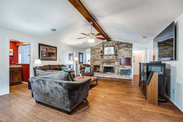 living room with lofted ceiling with beams, ceiling fan, light wood-type flooring, and a fireplace