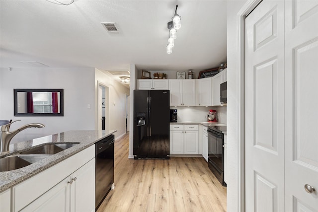 kitchen with white cabinetry, sink, light stone counters, and black appliances